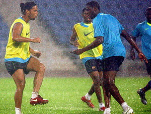 Los jugadores del Barça se entrenan bajo una intensa lluvia. (Foto: EFE)