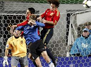 Casillas, al fondo, observa el salto de Juanito y Puyol. (EFE)