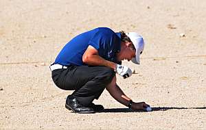 Este torneo se juega en el desierto y a veces la bola se escapa a la arena. Mickelson la coloca para golpearla (Foto: AFP).