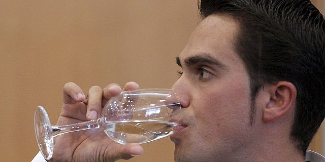 Alberto Contador bebe durante su conferencia de prensa. (Efe)