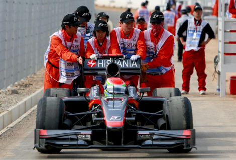 Varios comisarios de pista empujan el coche de Yamamoto. Foto: Efe