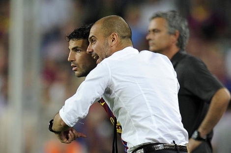 Pep Guardiola da instrucciones a Cesc, ante Mourinho. (EFE)