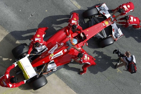 Varios mecnicos ayudan a Alonso a meter el coche en el garaje. | Reuters