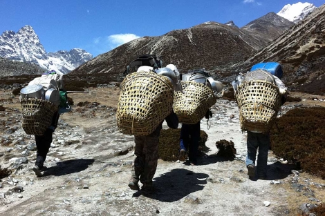 Un grupo de porteadores marcha cargado hacia el campo base del Everest.