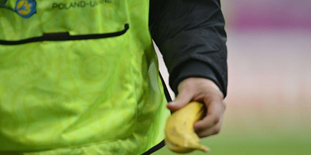 El 'steward' porta en la mano el platano lanzado al csped del estadio de Poznan. | Afp