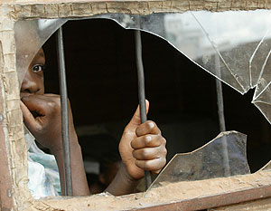 Una chica mira por el cristal roto de un centro para huérfanos del sida en Zimbabue. (Foto: AP)