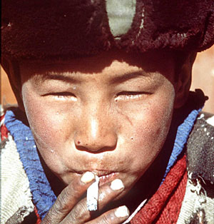 Un niño tibetano fuma un cigarrillo