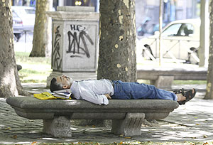 Un hombre duerme sobre un banco en el Paseo del Prado. (Foto: Diego Sinova)