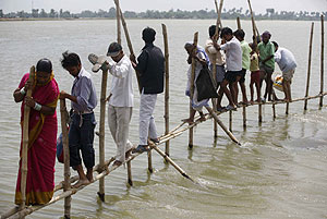 Los habitantes de una zona afectada caminan por un puente de bambú. (Foto: Reuters)