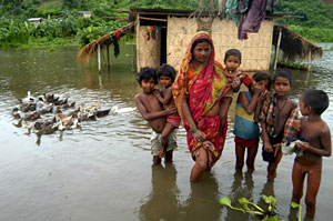 Una familia es fotografiada frente a su casa inundada en Chandrapur, en la India. (Foto: EFE)