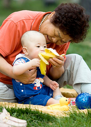 Una mujer da de comer un pltano a su hijo en un parque de Pekn. (Foto: EFE)