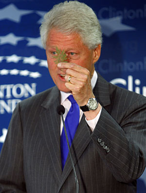 Bill Clinton muestra una hoja de la planta de la artemisina durante la rueda de prensa. (Foto: Brendan McDermid | Reuters)