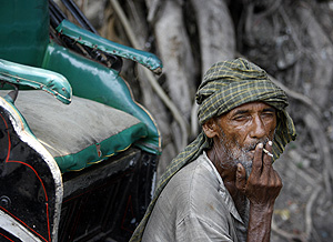 Un conductor del tradicional 'rickshaw' fumando en Calcuta (Foto: AFP | Deshakalyan Chowdhury)