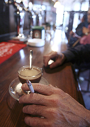 Un hombre fuma un cigarrillo y toma un caf en un bar. (Foto: EL MUNDO)