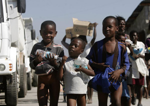 Un grupo de niños carga botellas de agua y paquetes de alimento en el reparto de suministros. (Foto: Orlando Barría)