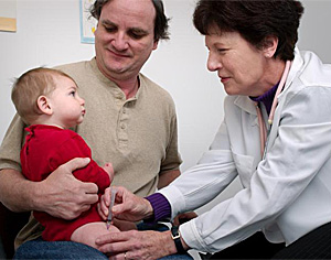 Un nio recibe una vacuna en brazos de su padre (Foto: CDC | Judy Schmidt)