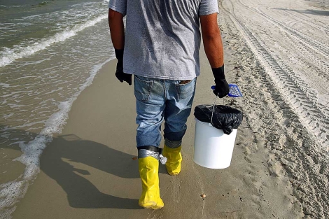 Un hombre recoge fuel en las costas de Alabama. | Win McNamee