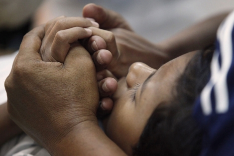 Un padre sujeta las manos de su hijo antes de la intervención.| Reuters