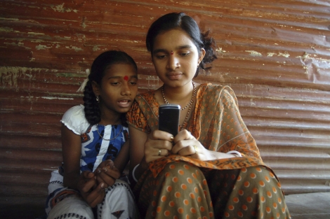 Dos chicas juegan con un mvil en la localidad de Tumni Pada, en Bombay (India). | Efe