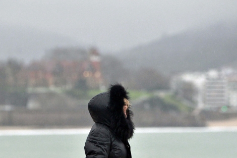 Una mujer se protege del fro y la lluvia en San Sebastin. | Efe