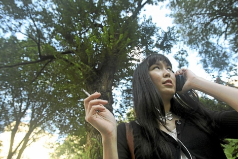 Una joven asiatica fumando en un parque. | AFP