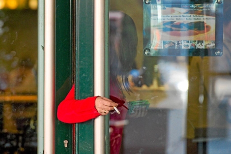 Una mujer fumando a las puertas de una cafetera.| Gonzalo Arroyo