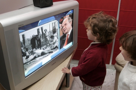 Dos niños atentos a las noticias de la televisión. | E. Lobato