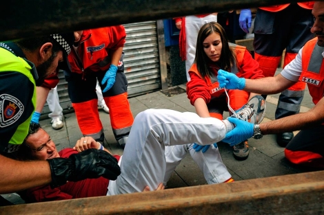 Varios tcnicos atienden a uno de los heridos en el encierro.| El Mundo