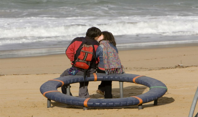 Una pareja de jóvenes besándose en la playa. | Justy García Koch