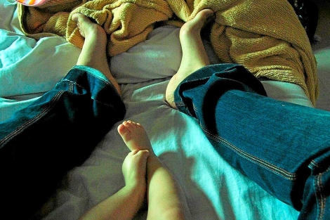 Un niño descalzo con su madre en la cama.|El Mundo