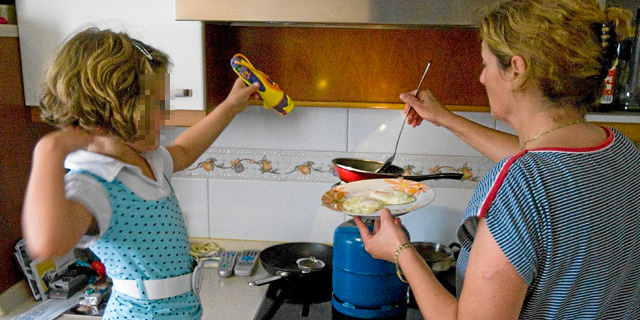 Una nia cocina con su madre durante un corte de luz.| El Mundo