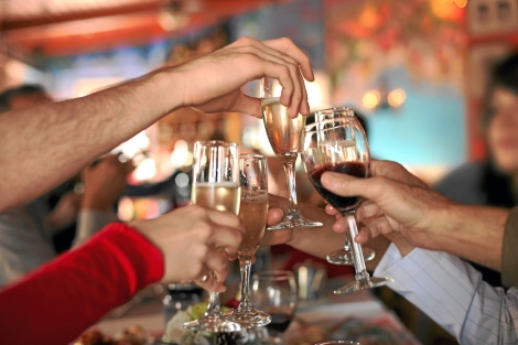 Varias personas brindan con copas de vino y champán. | Shutterstock