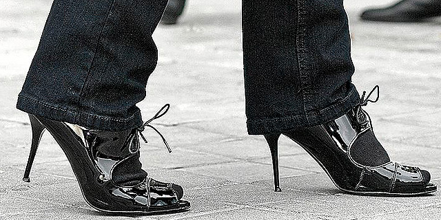 Pies de mujer calzados con zapatos de tacón alto.