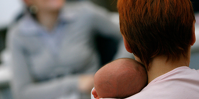 Un recién nacido reposa su cabeza en el hombro de su madre