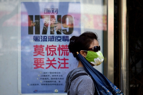 Una mujer pasea delante de un cartel que explica cmo evitar la infeccin por H7N9. | Afp