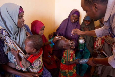 Un mdico vacuna contra la polio a un nio somal ante la presencia de su madre y otros nios