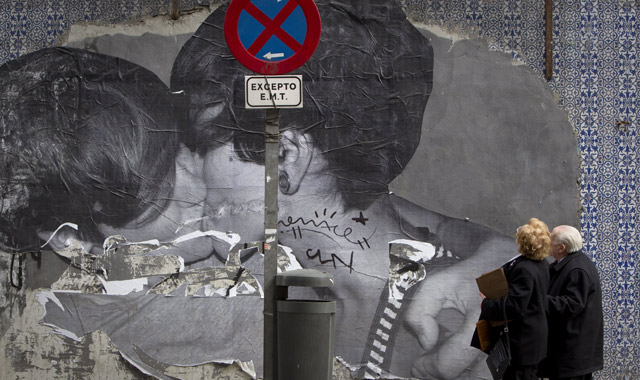 Una pareja de ancianos observa un grafitti donde dos jóvenes se besan