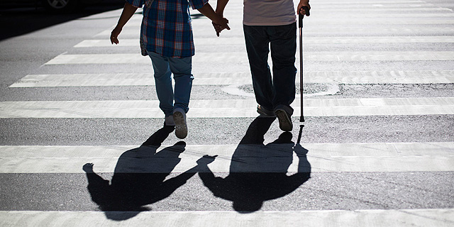 Una pareja cruza la calle con la ayuda de una muleta.| Lucas Jackson