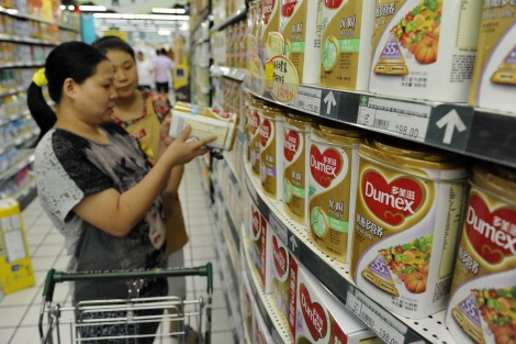 Una mujer mira una de las latas de leche Dumex en un supermercado de china. | Reuters