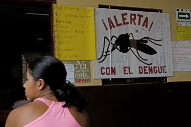 Una mujer frente a un cartel con instrucciones sobre el dengue. | MSF