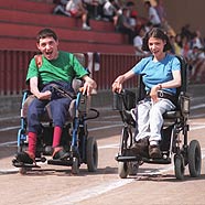 Foto de un chico y una chica en silla de ruedas haciendo una carrera