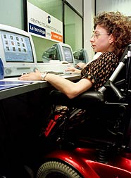 Una imagen de una chica minusvalida escribiendo en el ordenador y atendiendo una ventanilla de informacion