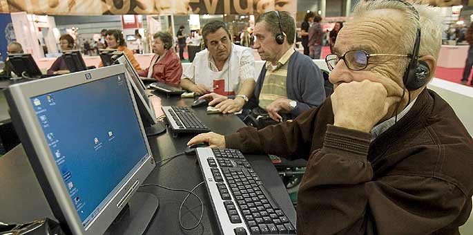 Voluntarios de la Cruz Roja ensean a ancianos a manejar el ordenador.