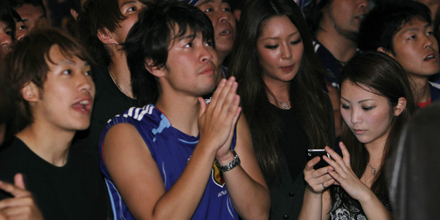 Una aficionada de Japn consulta su mvil en el transcurso del partido de Japn. | AP Photo