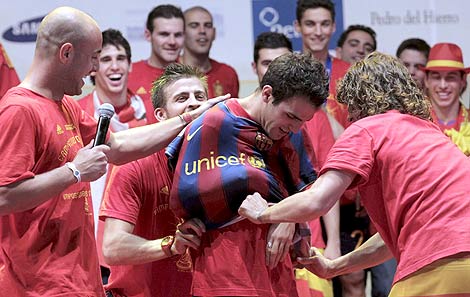 Puyol y Piqu ponen la camiseta del Bara a Fbregas, durante la celebracin. | Efe