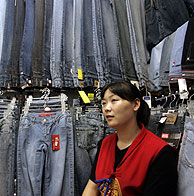 Una vendedora sentada entre pantalones vaqueros en un mercado de ropa de Pekín, China. (Foto: EFE)