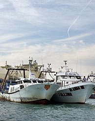 Varios barcos pesqueros impiden la salida de un gran barco mercante coreano en la bocana sur del puerto de Barcelona. (Foto: EFE)