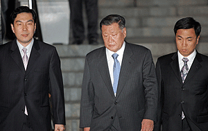 El presidente de Hyundai entre dos oficiales que le conducan hacia un centro de detencin preventiva. (Foto: Reuters)