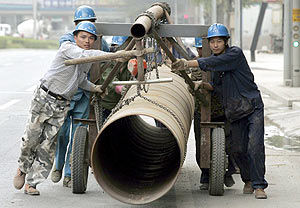 Trabajadores chinos transportan una enorme tubera en una obra en Pekn. (Foto: EFE)