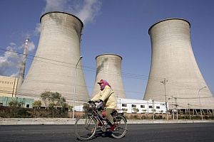 Un ciclista pasando delante de las torres de enfriamiento de una planta eléctrica en Pekín. (Foto: EFE)
